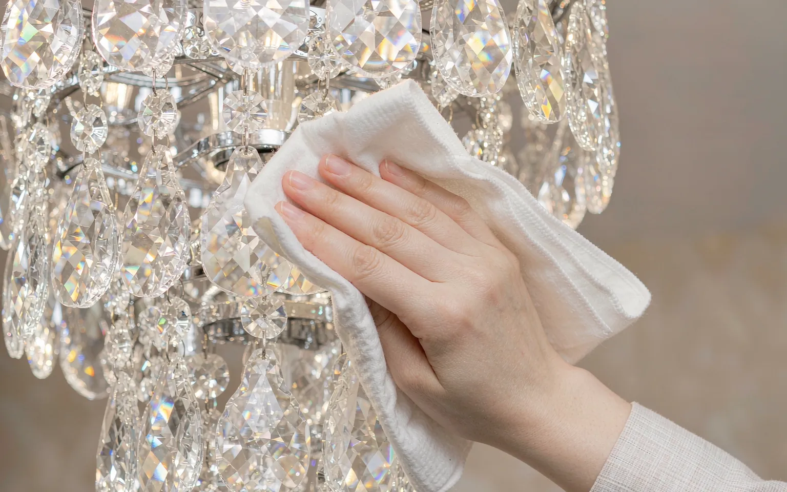 Hand cleaning a crystal chandelier with a microfiber cloth
